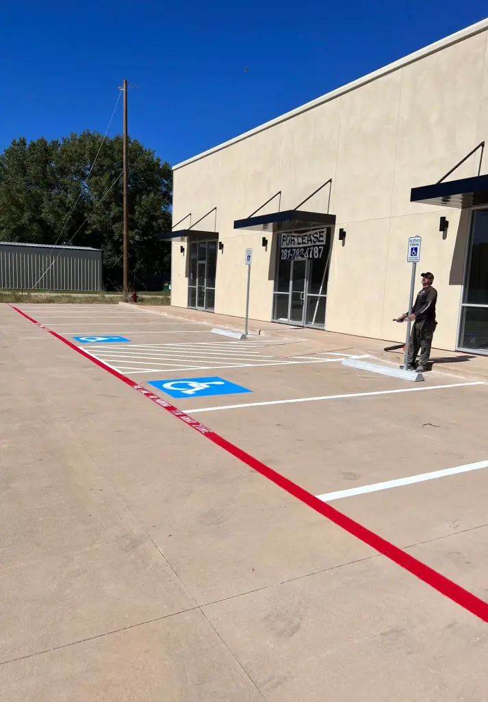 A newly striped parking lot with blue ADA spaces and a red fire lane in front of a commercial building