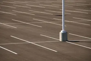 Fresh white stall lines on dark asphalt around the base of a parking lot light pole