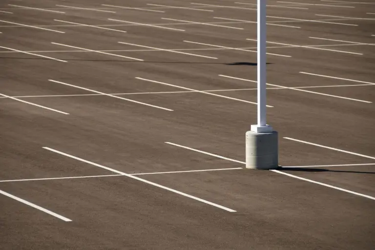 Fresh white stall lines on dark asphalt around the base of a parking lot light pole