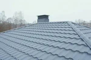 A gray metal tile roof with a chimney cap