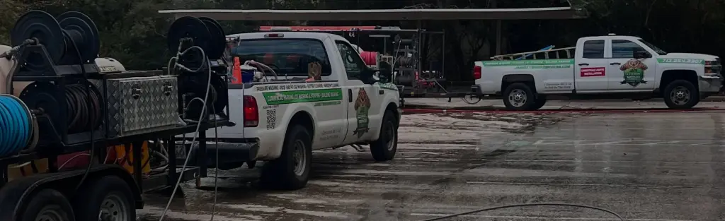 Two Jade Exterior Services trucks and equipment trailers parked at the shop