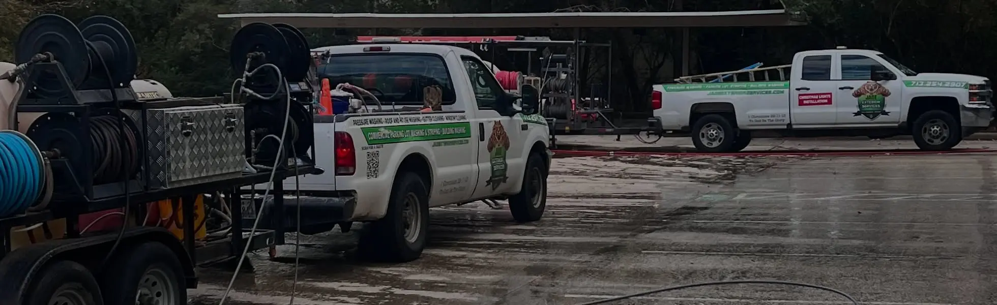 Two Jade Exterior Services trucks and equipment trailers parked at the shop