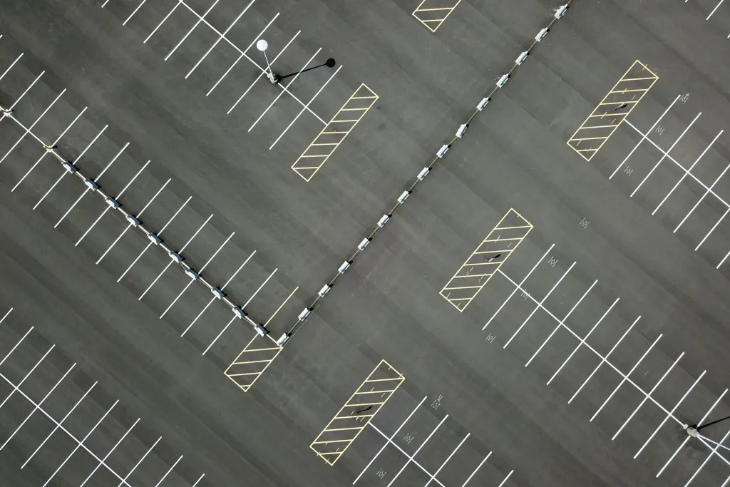 An overhead view of a parking lot with white stall lines and yellow hatched no parking areas