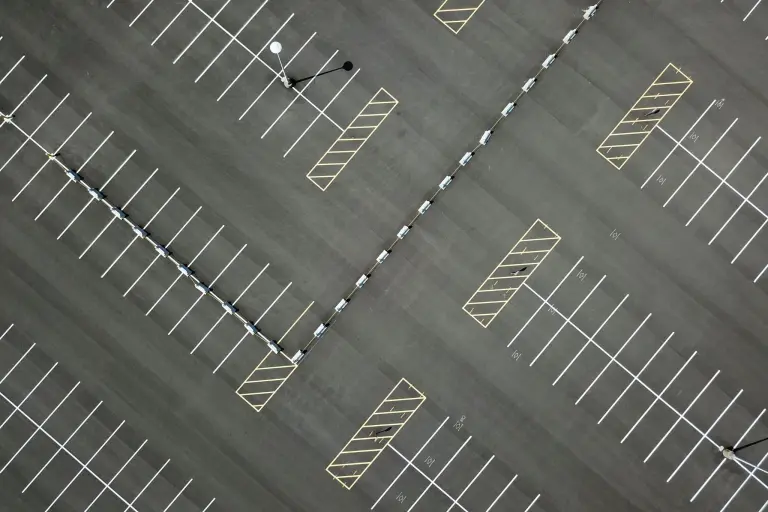 An overhead view of a parking lot with white stall lines and yellow hatched no parking areas