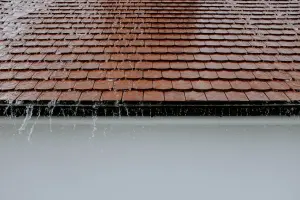 Water running off the eave of a red tile roof