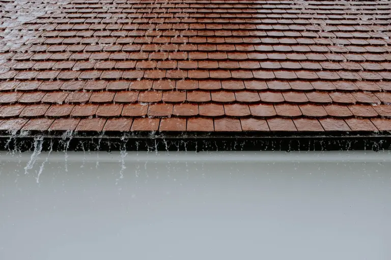 Water running off the eave of a red tile roof