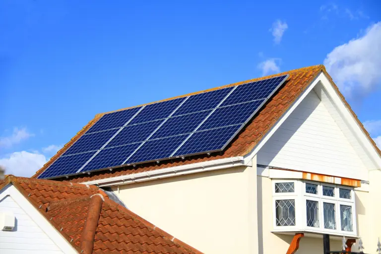 Solar panels mounted on the terracotta tile roof of a cream colored house