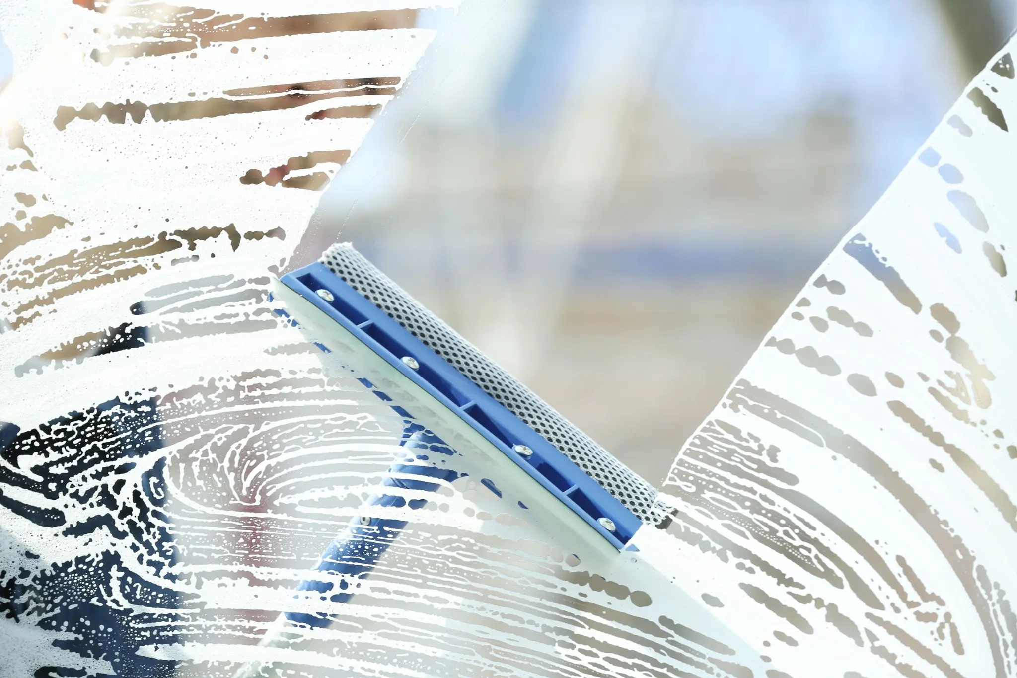 A squeegee clearing suds from a pane of glass